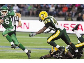 Brett Smith, left, who will start at quarterback Friday, dodges an attempted tackle by Edmonton Eskimos' Ryan Hinds, bottom, and Deon Lacey in pre-season.