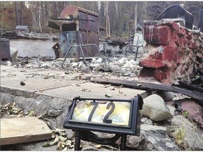 A burned out cabin at Waden Bay, 380 kilometres north of Saskatoon, on Saturday. Changing winds are making it difficult to control the persistent fires.