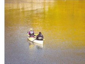 A canoeing couple drift through the season's changing colours with the river's current after paddling up to the South Circle Drive Bridge on Tuesday.