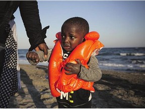 A child from Gambia is helped ashore after arriving on the Greek island of Kos in a dinghy on Sunday. Some governments have called on the EU to set up migrants' reception centres