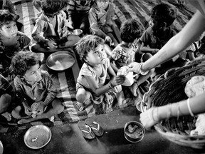 Children are served flatbreads, part of a meal that includes a scoop of boiled potato curry at a government-run program serving lunch in Madkheda, Madhya Pradesh state, India.