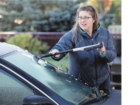 Christine Sidebottom scrapes the frost from her vehicle on 116th Street in Sutherland, Tuesday after a little frost overnight.