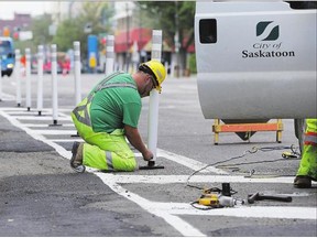 City workers install bollards indicating separated bikes lanes along 23rd Street downtown Monday in Saskatoon.
