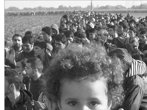 A column of migrants moves through fields after crossing from Croatia, in Rigonce, Slovenia on Sunday. Experts say the new Liberal government's plan to resettle 25,000 Syrian refugees by the end of 2015 may be a little too ambitious.