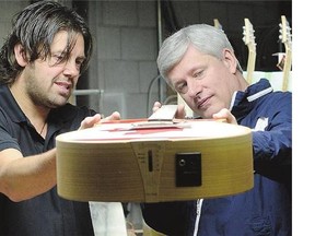 Conservative Leader Stephen Harper checks out an acoustic guitar with Mike Miltimore, owner of Riversong guitar company, in Kamloops, B.C., on Monday.