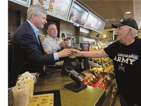 Conservative Leader Stephen Harper serves coffee at a Tim Hortons in Gananoque, Ont., Monday. Harper said he wouldn't get into a discussion about a potential recession.