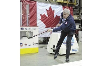 Conservative Leader Stephen Harper takes a shot during a campaign stop at a company that makes boards for hockey rinks in Port Moody, B.C., Tuesday.