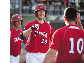 Derek Mayson, centre, celebrates with his Team Canada teammates after scoring against Guatemala during the 14th Men's World Softball Championship in Saskatoon, Friday. Canada won 6-0. See the story see on Page B1.