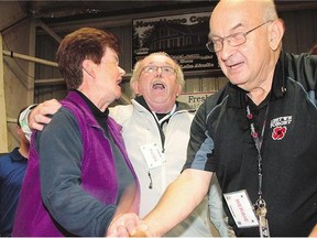 Donelda MacAskill, 62, of Englistown, N.S., celebrates with volunteers Keith MacMillan, centre, and Herbie Jeromel after flipping over the ace of spades and winning more than $1.7 million in Inverness, N.S., on Saturday.