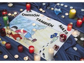 A drawing depicting three-year-old Alan Kurdi reads 'Omission also kills' during a candle-light tribute Friday in Barcelona.