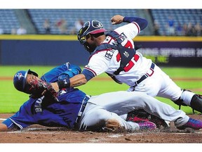 Edwin Encarnacion of the Toronto Blue Jays slides by the tag of Atlanta Braves catcher Christian Bethancourt during game Wednesday in Atlanta.