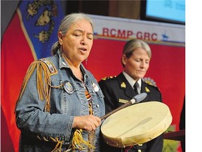 Elder Barbara Hill drums at the release of the RCMP Missing and Murdered Aboriginal Women: 2015 Update on Friday, as Deputy Commissioner Janice Armstrong stands behind.