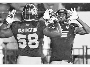 Eskimos Tony Washington, left, and Adarius Bowman celebrate a touchdown against the Calgary Stampeders in Edmonton on Saturday. Edmonton's win could prove to be quite expensive for one family that has been wagering on the outcome of the rivals' games each season since 2012.