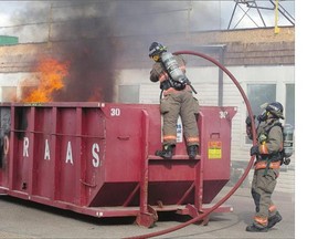 Firefighters extinguish flames in a Loraas disposal bin at the Saskatchewan Abilities Council building on Kilburn Avenue on Monday,
