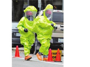 Firefighters in haz-mat gear enter a building on Spadina Crescent where a small cylinder containing toxic gas accidentally leaked Wednesday.