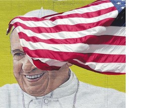 A US flag blows in the wind in front of a mural of Pope Francis across the street from Madison Square Garden in New York as the city prepares for his visit.