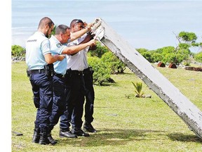 French police officers inspect what is believed to be a 'flaperon' from the trailing edge of a Boeing 777 wing Wednesday in Saint-Andre on the French island of Reunion.