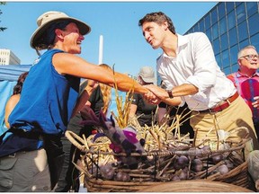 Garlic vendor Anna Schaab, left, shakes hands with Liberal Leader Justin Trudeau during a campaign visit to the Regina Farmers' Market on Wednesday.