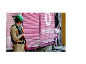 A girl watches from the gate of her house as an Indian soldier stands guard while a curfew is imposed in Srinagar, India, on Friday. Authorities are enforcing a curfew in parts of Indian-controlled Kashmir after a series of killings.