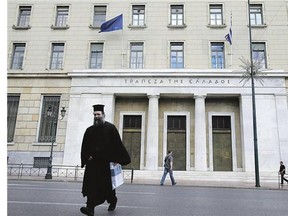 A Greek Orthodox priest crosses the street outside of Bank of Greece headquarters in Athens. Many Greeks remain convinced that the EU, the IMF and the European Central Bank will once again come through with funds at the last minute, as happened in 2012.