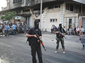 Hamas security members stand guard near a vehicle destroyed in a blast in Gaza City on Sunday.