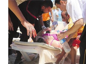 Injured people are treated on a Tunisian beach in Sousse on Friday. A young man unfurled an umbrella and pulled out a Kalashnikov rifle, opening fire on European sunbathers in one of three deadly attacks from Europe to the Middle East that killed more than 80 people.