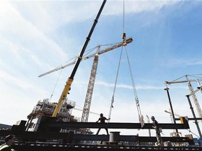 Iron workers lift steel columns at the site of the new stadium in Regina. Projects like this during economic boom times have attracted many out-of-province workers.