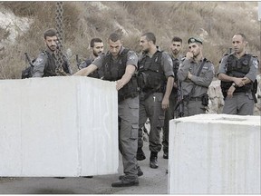 Israeli border police officers help place concrete blocks on the road at the entrance to the East Jerusalem neighbourhood of Jabal Mukaber. The Israeli military began deploying hundreds of troops in cities across the country on Wednesday.