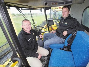 James Schultz, right, and Rick Rivett of Moody's Equipment sit in a New Holland combine which contains a GPS display, on Tuesday. Guidance tools and automated steering systems are helping farmers cut operating costs.
