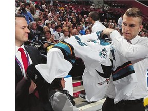 Jeremy Roy puts on his jersey after being selected 31st overall by the San Jose Sharks on Saturday in Sunrise, Fla.