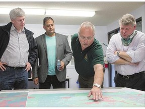 John deBruin, senior fire manager, second from right, explains a fire map to, from left, Prime Minister Stephen Harper, MP Rob Clarke, and MP Randy Hoback during a visit to the wildfire management centre in the La Ronge firehall on Friday.