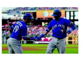 Jose Bautista, left, of the Toronto Blue Jays congratulates teammate Josh Donaldson on his first-inning homer during MLB action in Philadelphia on Tuesday. Donaldson finished the night with two as the Jays won 8-5.