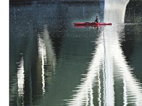 A kayaker drifts underneath the University Bridge surrounded by reflections of the bridge supports on a balmy October Friday in Saskatoon.