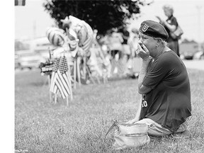 Laurie Norman becomes emotional as she looks at a makeshift memorial outside a military recruiting centre Friday where a gunman opened fire in Chattanooga, Tennessee, killing four members of the U.S. Marines.