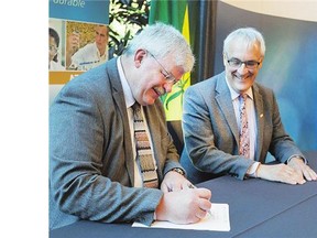 Laurier Schramm, left, of the Saskatchewan Research Council, and Dr. Roman Szumski of the National Research Council, sign an agreement Thursday to officially mark the collaboration between the two councils.