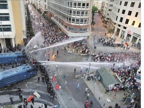 Lebanese activists shout antigovernment slogans as they are sprayed by riot police using water cannons during a protest in downtown Beirut on Sunday.
