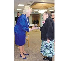 Lieutenant-governor Vaughn Solomon Schofield, left, presents 100-year-old Charlotte Ayers with a birthday gift at Broadway Terrace in Regina on Wednesday.