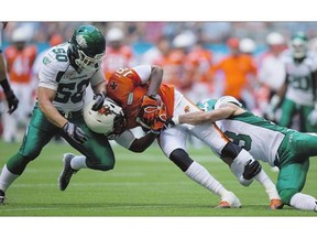 B.C. Lions' Cameron Morrah, centre, is tackled by Saskatchewan Roughriders' Jake Doughty, left, and Macho Harris during the first half of their game in Vancouver on Friday.