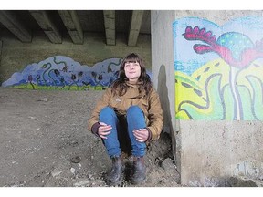 Local artist Laura Hosaluk under the Broadway bridge with her mural Community Garden. She collaborated on the project with Nutana residents and business owners.