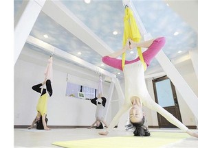 Manao, front, takes on an aerial yoga pose using a hammock
