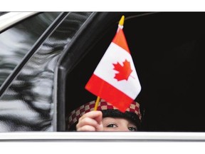 Marcus Cirillo, son of Cpl. Nathan Cirillo, waves a flag out of a car window following the funeral service for his father in Hamilton, Ont. last year.