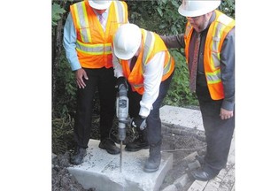 Montreal Mayor Denis Coderre, centre, uses a jackhammer to destroy a concrete foundation laid for a community mailbox at the entrance to Anse-a-l'Orme Nature Park, in Montreal, on Thursday.