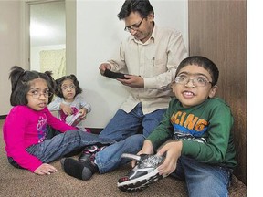 Muhammad Akhter, second from right, helps his children, from left, Khadija, Sara and Muhammad on with their shoes.