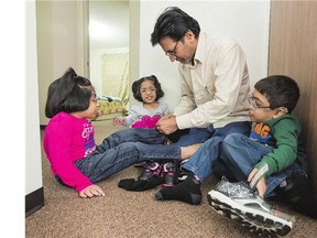 Muhammad Amir Akhter helps his children, from left, Khadija, Sara and Muhammad Abdullah put their shoes on before heading to school at River Heights. The provincial health ministry is reconsidering drug funding for the children, who have an enzyme disorder.