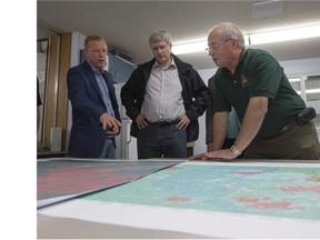 John deBruin, Senior Fire Manager, right, explains a fire map to Prime Minister Steven Harper, centre, and Saskatchewan Premier Brad Wall during a visit to the wildfire management centre in La Ronge, Sask., fire hall on Friday, July 24, 2015. THE CANADIAN PRESS/Liam Richards