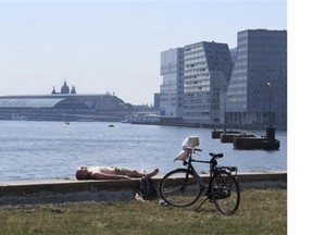 A man sunbathes near his bicycle on the waterfront of IJ harbour in Amsterdam, Saturday, July 4, 2015, during a heatwave with temperatures rising to 36 degrees Celsius around noon.