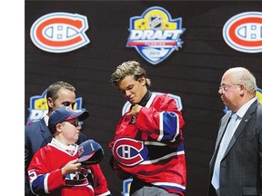 Noah Juulsen puts on a Montreal Canadiens sweater after being chosen 26th overall by the Canadiens during the NHL draft on Friday in Sunrise, Fla. The defenceman was a teammate of Habs 2014 draftee Nikita Scherbak.