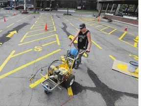 Painting by the numbers, Eric Ellsworth paints the lines in the parking lot of the Saskatoon Funeral Home, Monday.