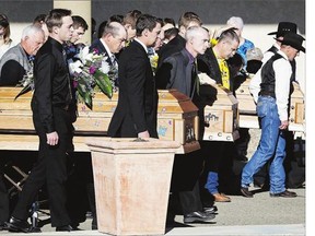 Pallbearers carry the coffins of Catie Bott, 13, and her twin 11-year-old sisters, Jana and Dara Bott in Red Deer, Alta. on Friday. The girls suffocated when they became buried in truck filled with canola last week on a farm near Withrow, Alta.