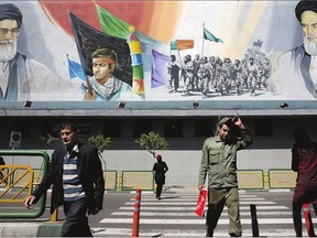 Pedestrians cross the Enqelab-e-Eslami (Islamic Revolution) street under a mural depicting Iranian revolutionary founder Ayatollah Khomeini, right, members of Basij paramilitary force, centre, and Supreme Leader Ayatollah Ali Khamenei, in Tehran, Iran.